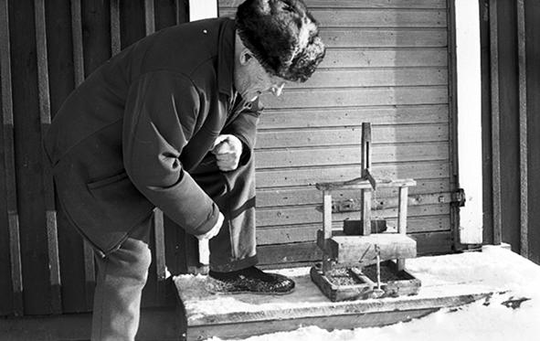 Mies esittelee puusta valmistettu hiirenloukkua.