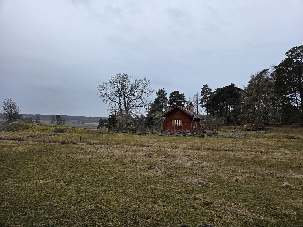 Sateisessa maisemassa metsistön edustalla näkyy punaiseksi maalattu sotilastorppa 1800-luvulta.